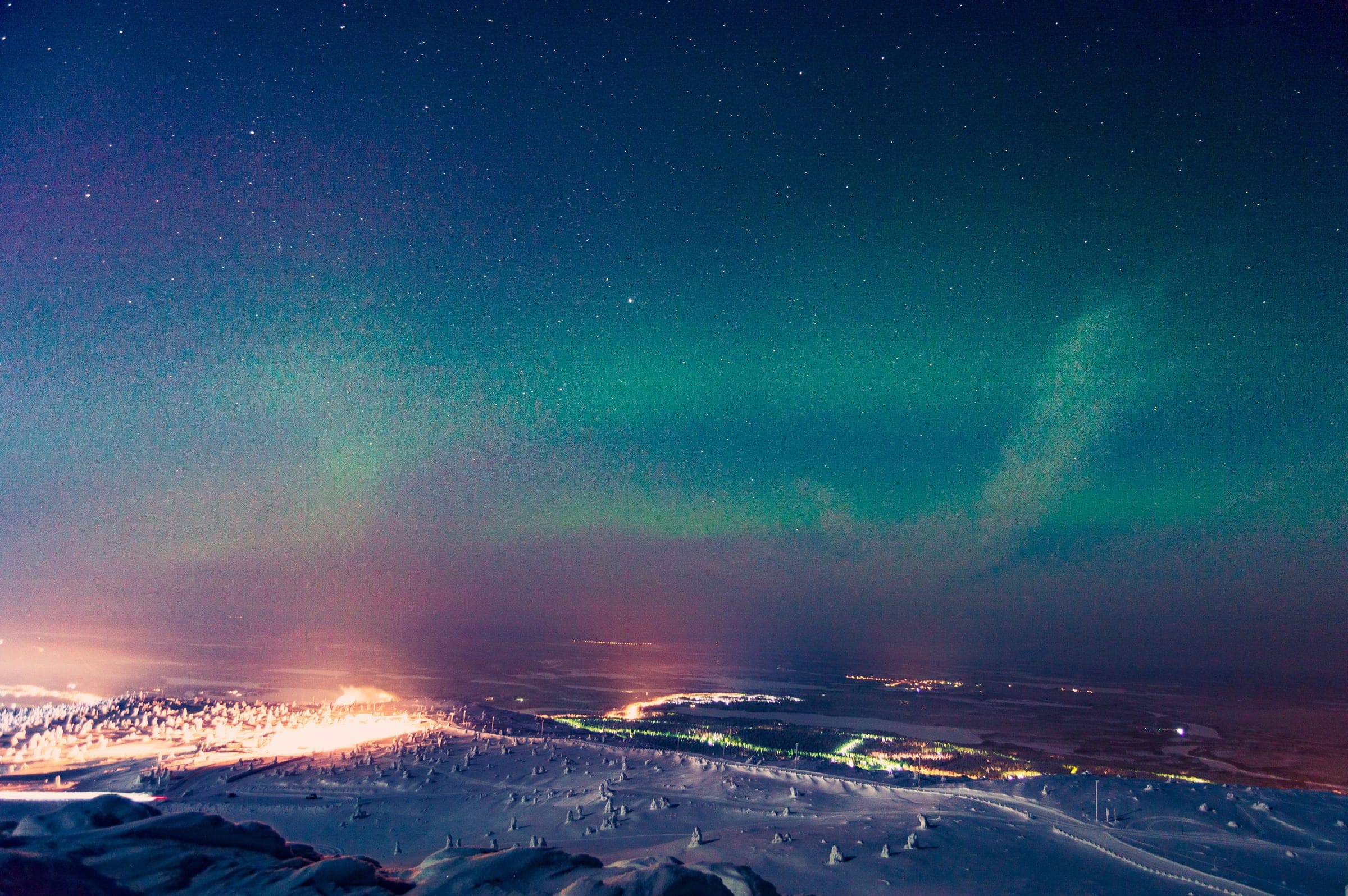 Auroras boreales sobre las luces del pueblo de Levi, vistas desde la colina