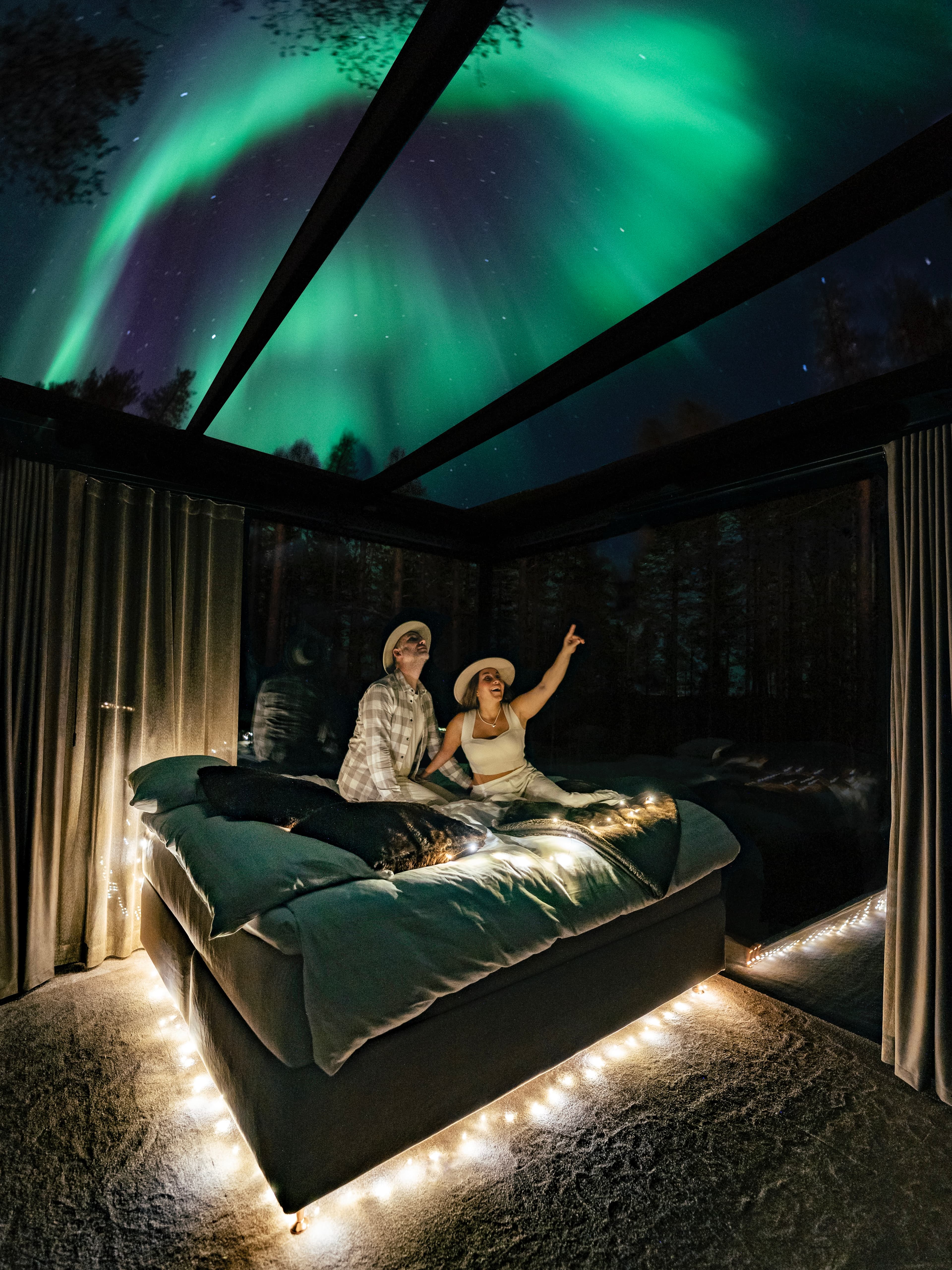 Couple enjoying the Northern Lights from a glass igloo